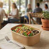 Person enjoying noodle meal in Zeropac Kraft Container at cafe table