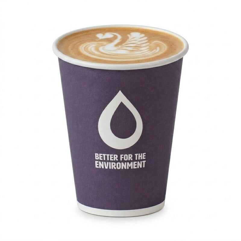 Hand holding Zeropac 12oz cup with cappuccino dusted with cocoa, croissant nearby