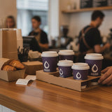 Cafe staff passing Zeropac recycled pulp cup carrier trays with coffee and pastries
