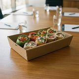 Kraft wrap catering tray on conference table at business meeting with water glasses and settings