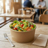 Salad in Zeropac kraft bowl on cafe table with fork and napkin