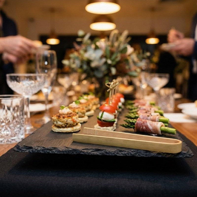 Chef using bamboo tongs to serve gourmet appetizers at formal dinner