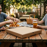 Couple sharing outdoor picnic with brown pizza box on wooden table