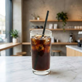 Black paper straw in cold cola on kitchen marble counter